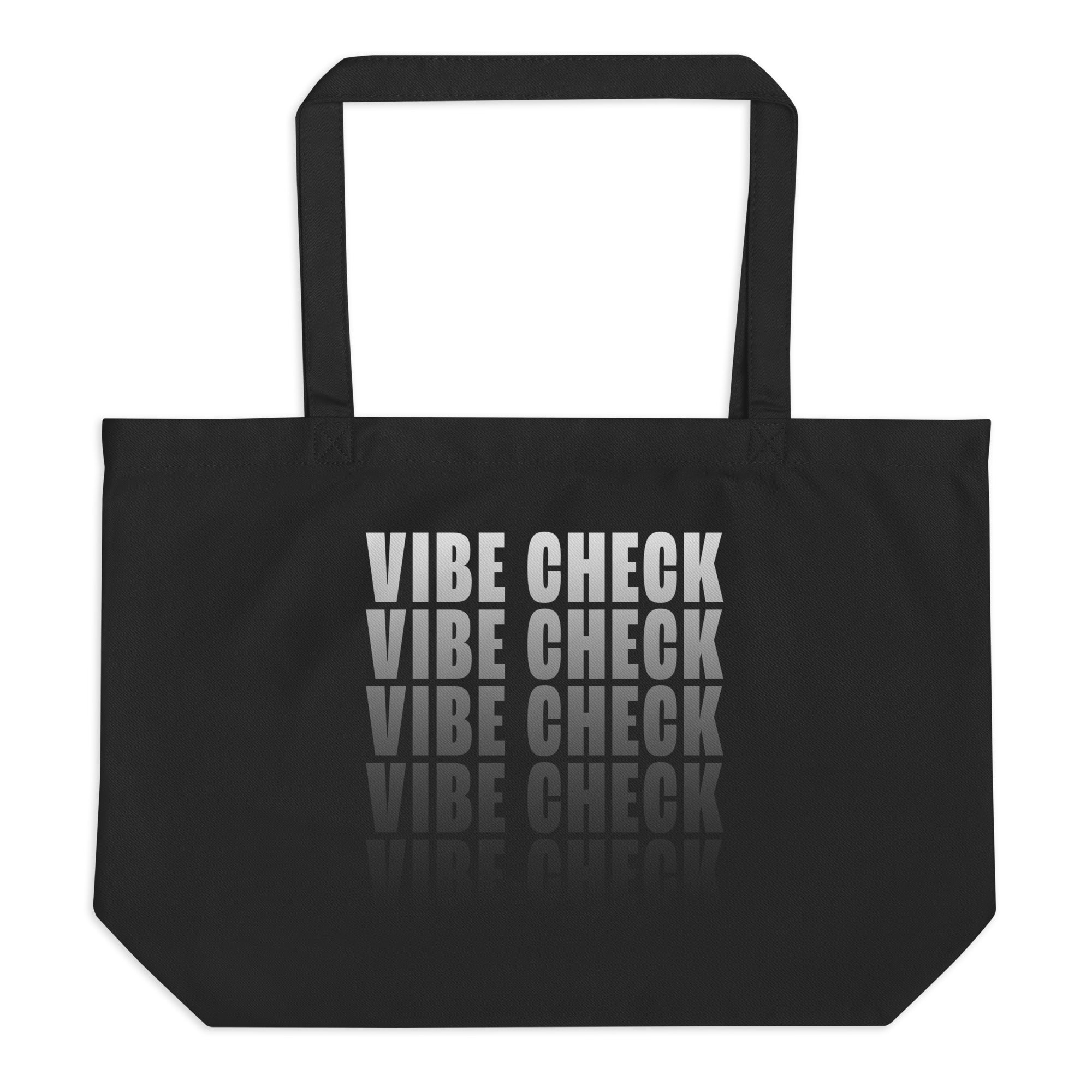 A black tote bag featuring bold white text that reads 'VIBE CHECK' in a stacked, repeating pattern with a reflection effect at the bottom. The bag has long handles and a spacious design.