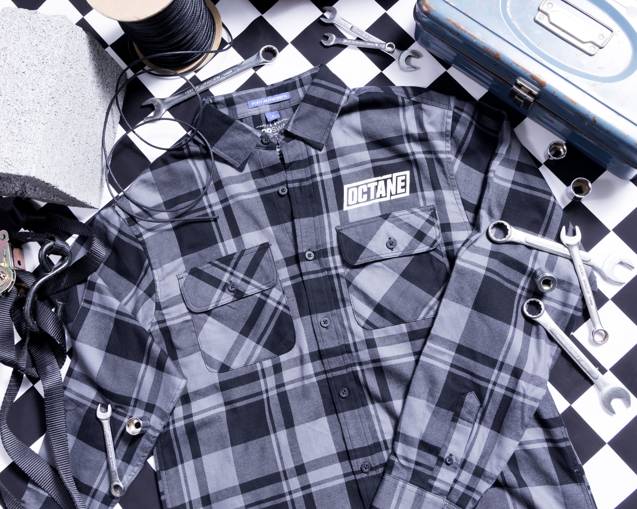 Gray and black plaid shirt with 'OCTANE' logo in white, surrounded by tools and materials on a checkered black and white background.