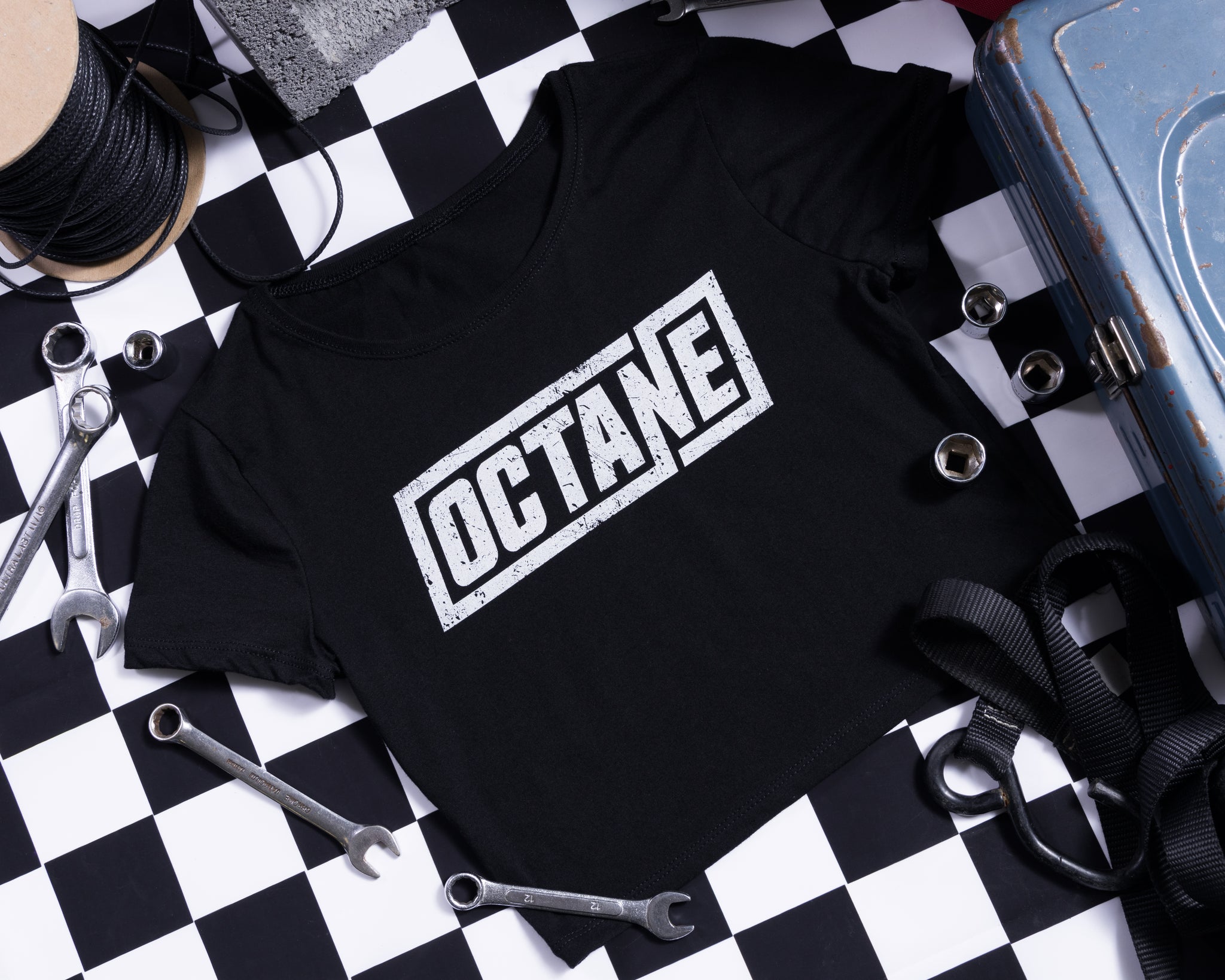 Black crop t-shirt with 'OCTANE' printed in white, surrounded by tools on a checkered background.