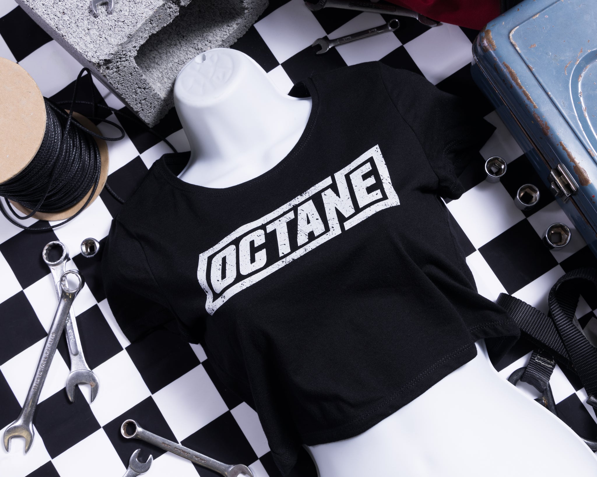 Black crop top with 'OCTANE' logo, surrounded by tools and materials on a checkered background.