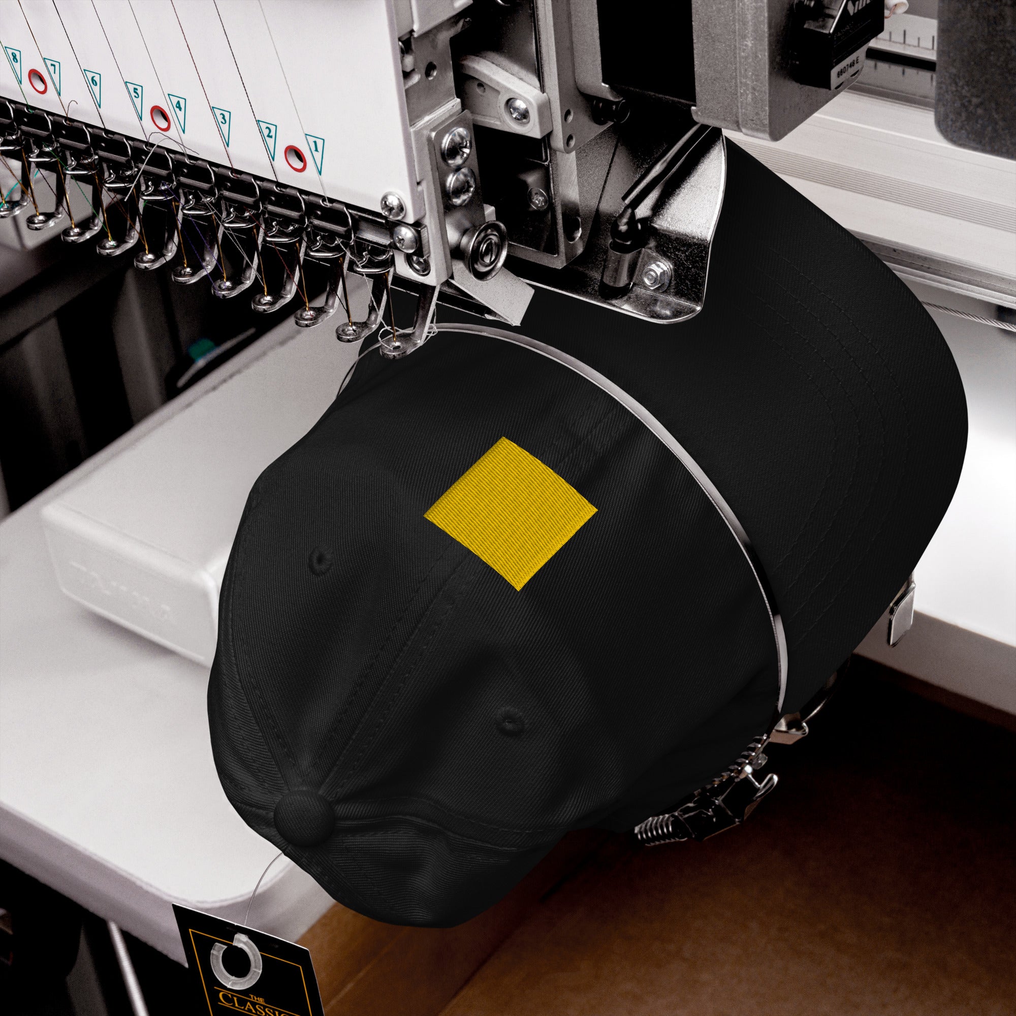 A black cap with a yellow square on a sewing machine