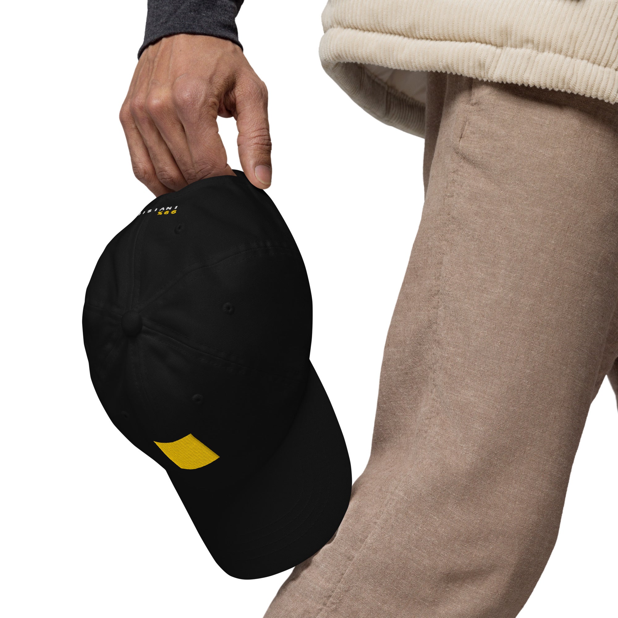 A person holding a black cap with a yellow square.