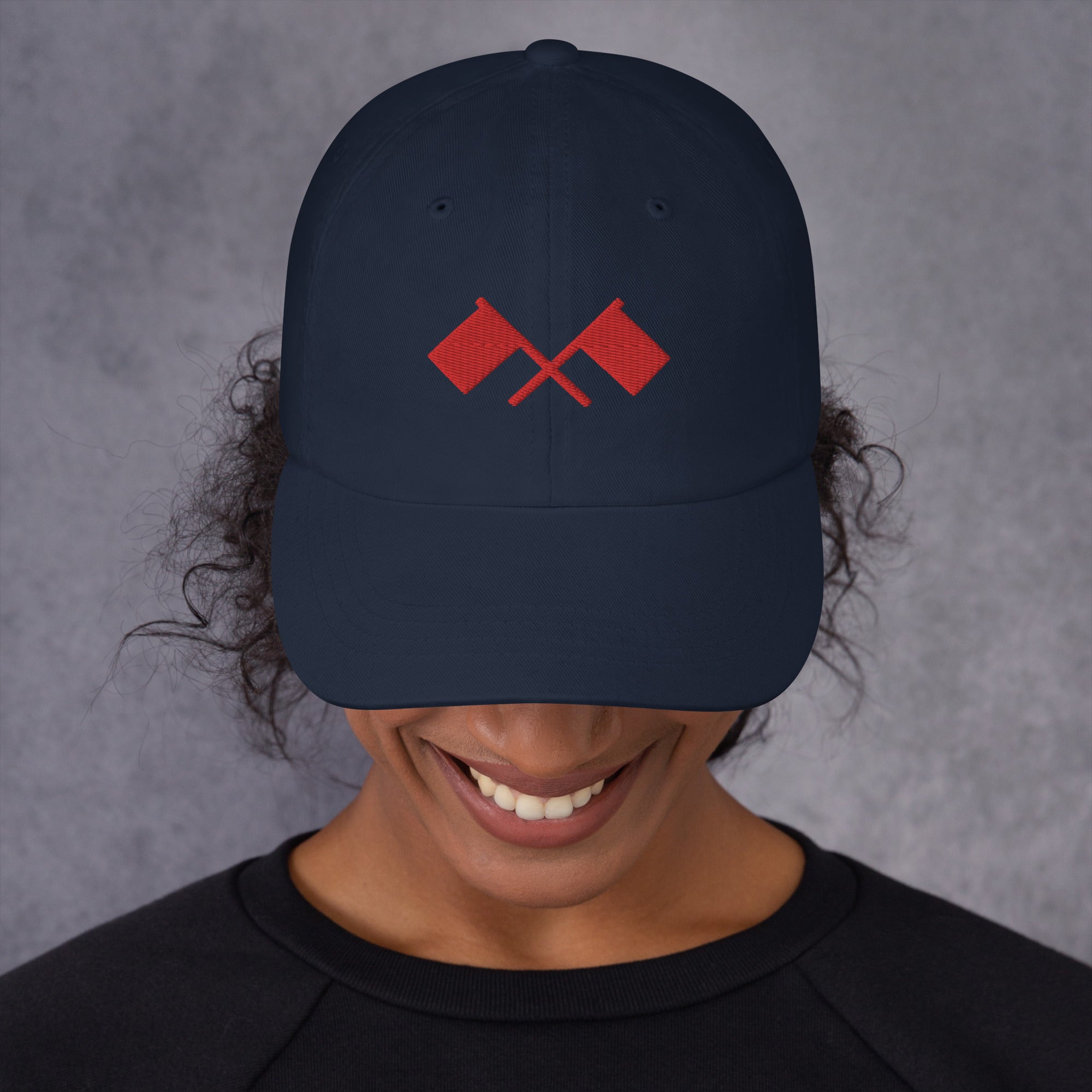 A person wearing a navy blue cap with a red crossed flag design.