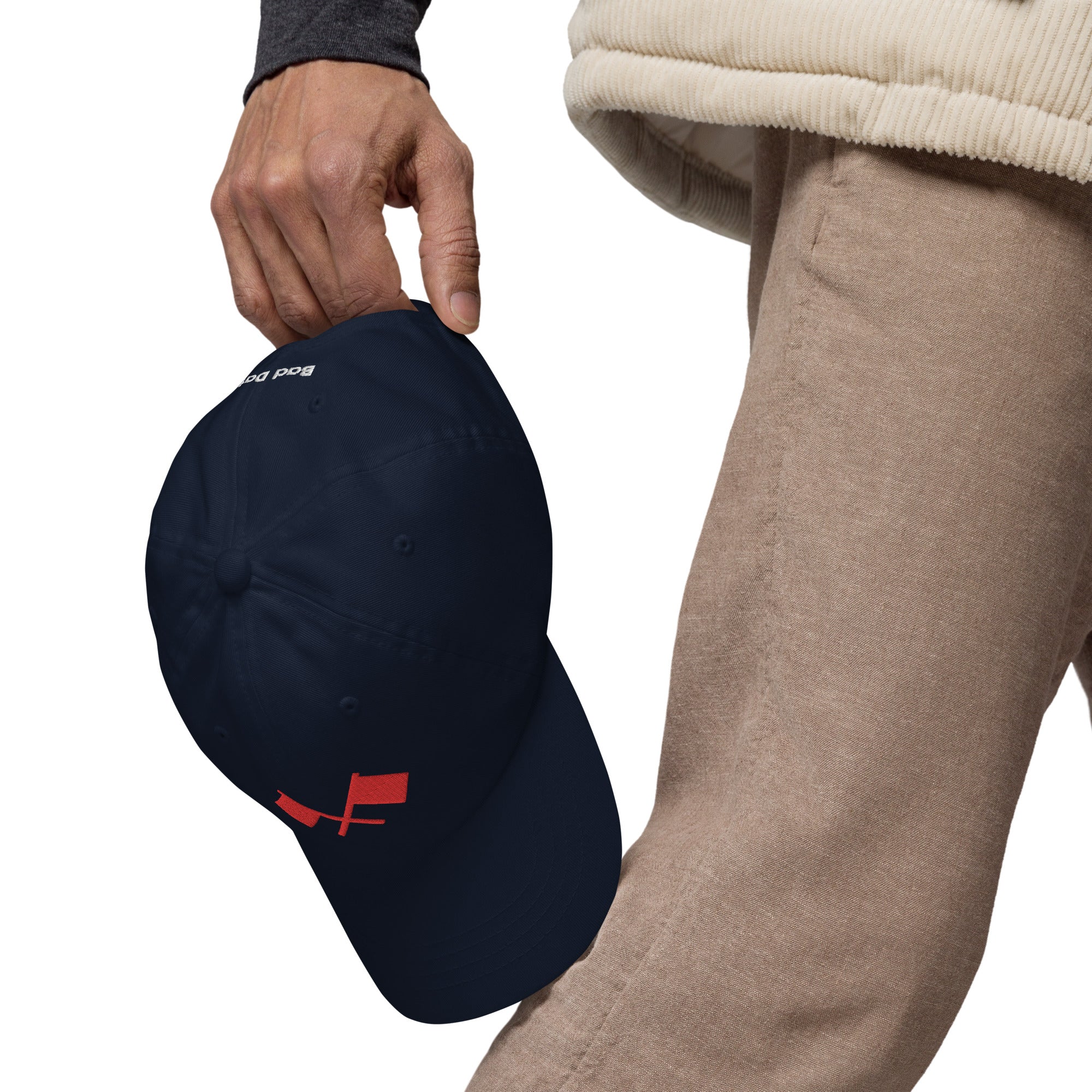 A person holding a navy blue baseball cap with a design of two red crossed flags.