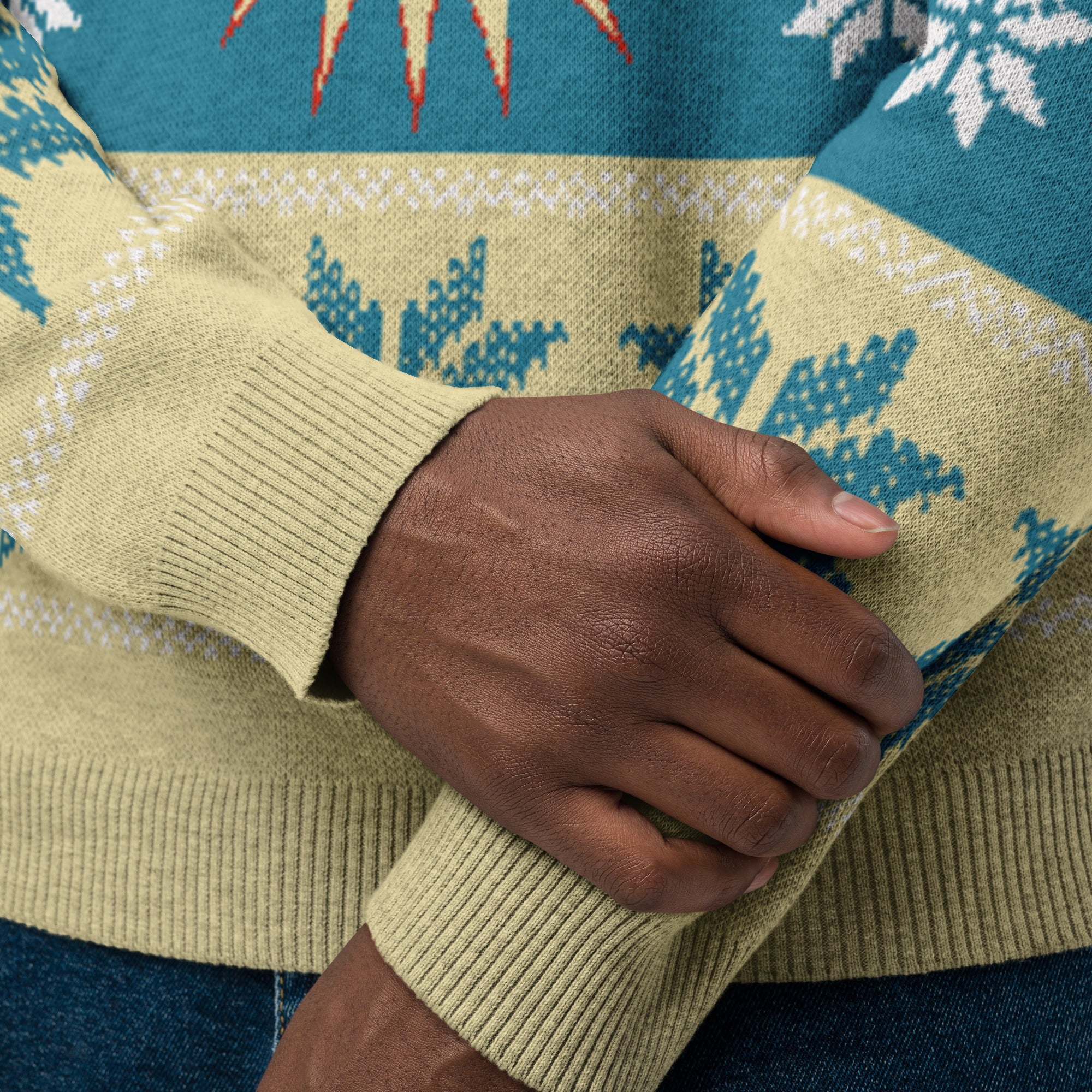 A close-up of a hand resting on a patterned sweater with shades of blue and yellow, featuring snowflake and geometric designs.