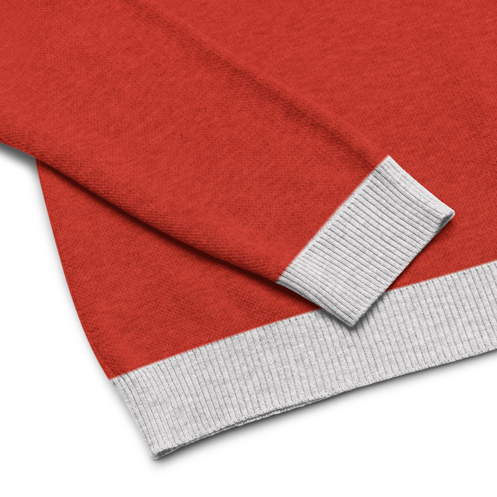 A close-up view of a red sweater with a contrasting light gray ribbed cuff and bottom hem.