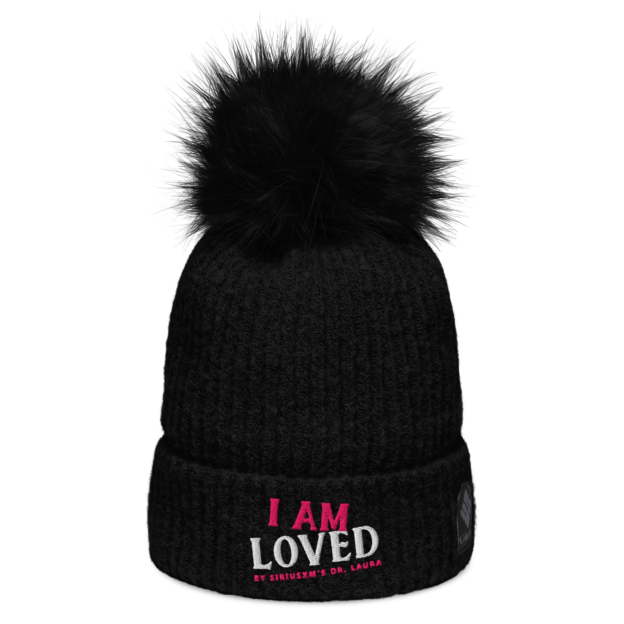 Black, ribbed beanie hat with matching, fluffy pom-pom on top and embroidered text on the cuff reading 'I AM LOVED,' with 'I AM' in pink and 'LOVED' in white lettering. Below, it says 'BY SIRIUSXM'S DR. LAURA' in smaller pink text.