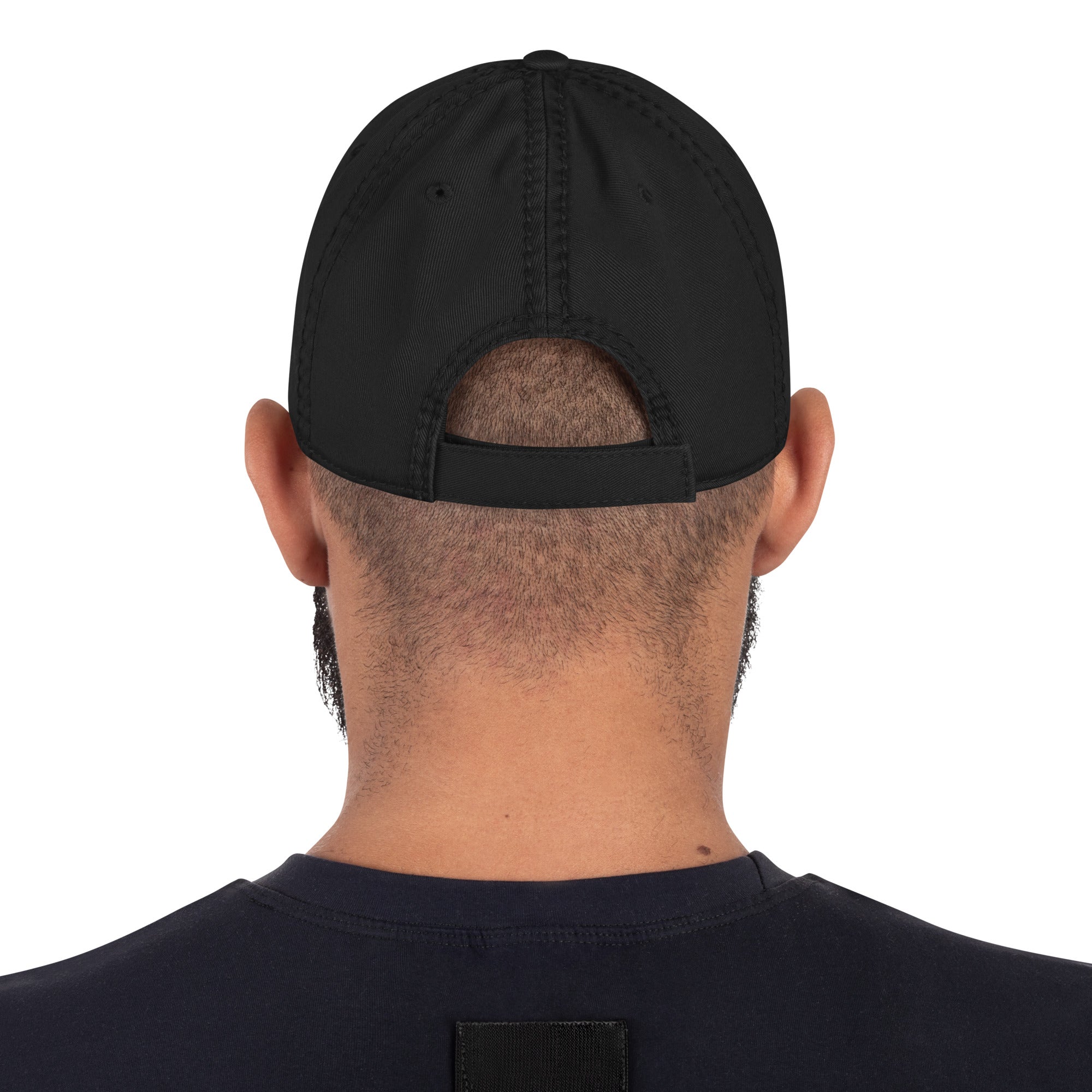 The back of a man's head displaying the backside of a black baseball hat and it's adjustable closure strap. 