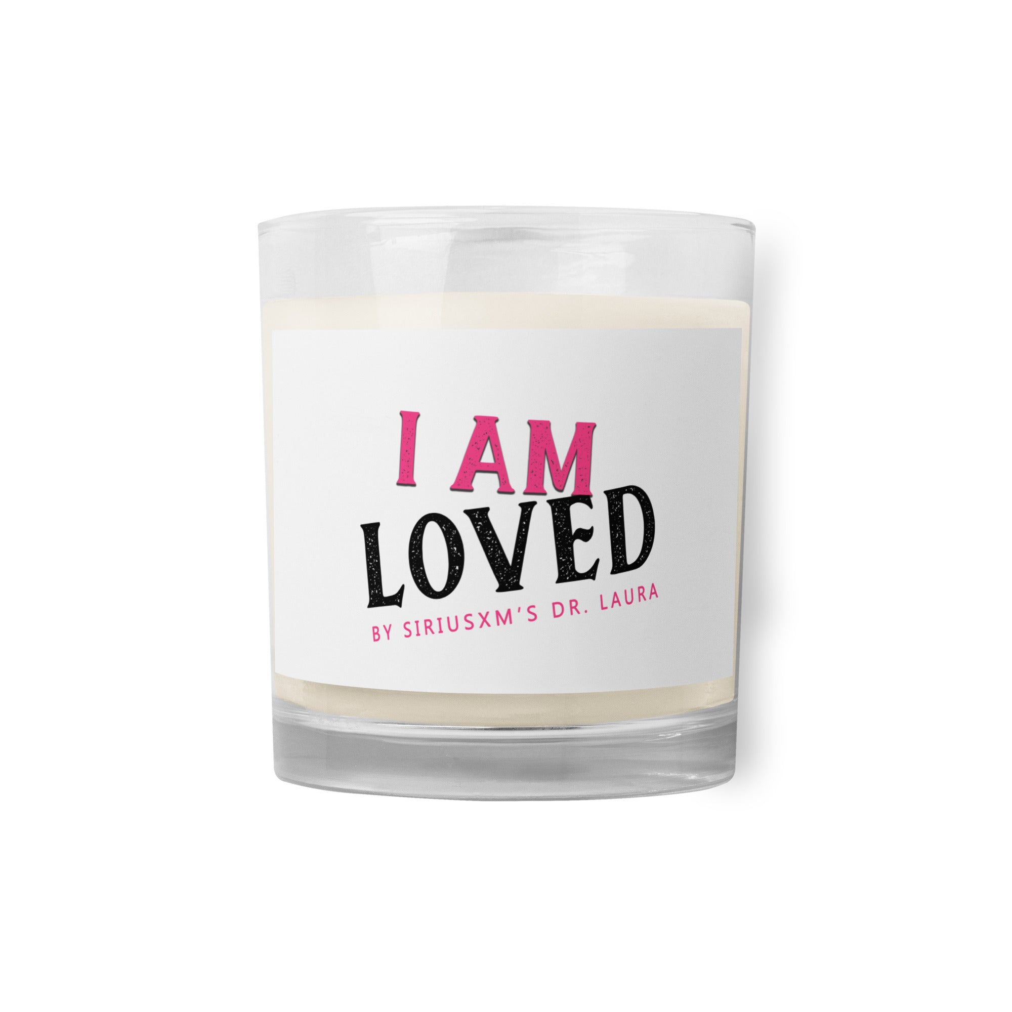 A clear glass jar candle with white soy wax inside. The label on the front reads 'I AM LOVED' in bold text, with 'I AM' in pink and 'LOVED' in black. Below, it says 'BY SIRIUSXM'S DR. LAURA' in smaller pink text.