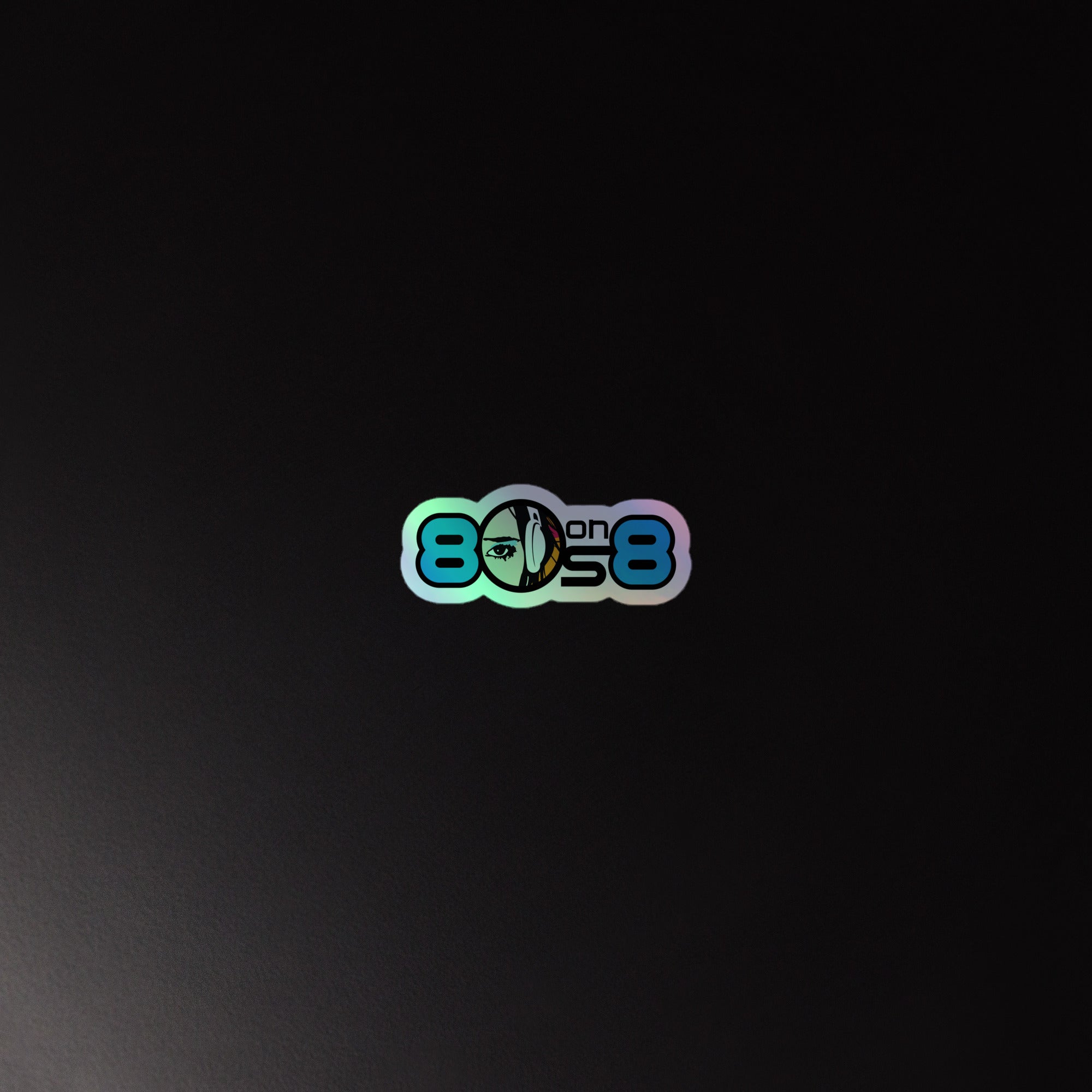 Holographic sticker of '80s on 8' logo featuring a partial face wearing headphones graphic, on a black background.