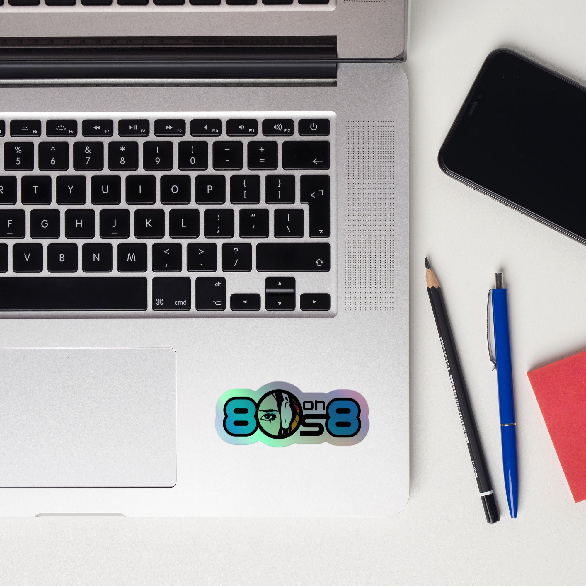 Laptop keyboard displaying a colorful '80s on 8' holographic sticker.