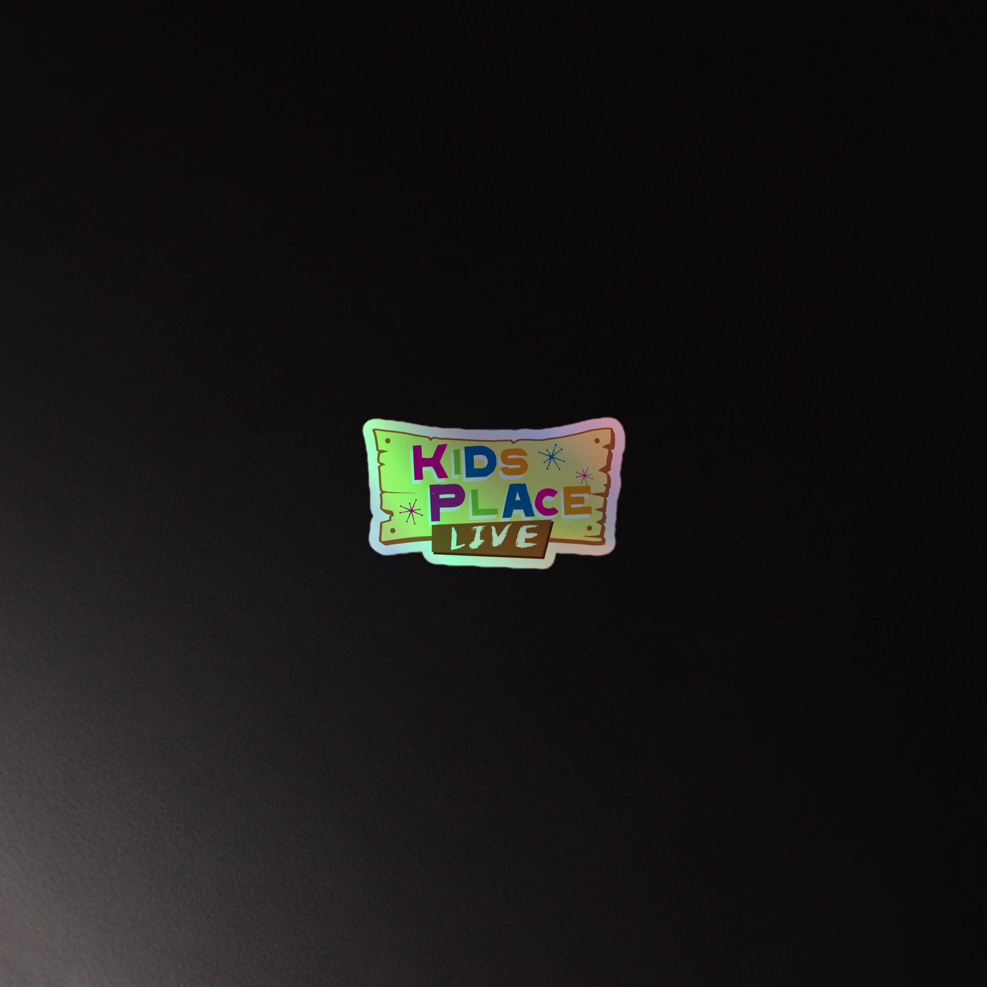 Holographic 'KIDS PLACE LIVE' sticker on a dark background.