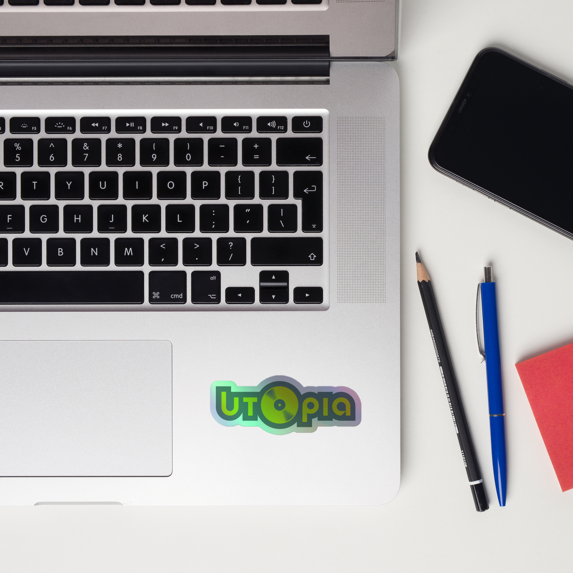 A laptop keyboard displaying a 'Utopia' holographic sticker.