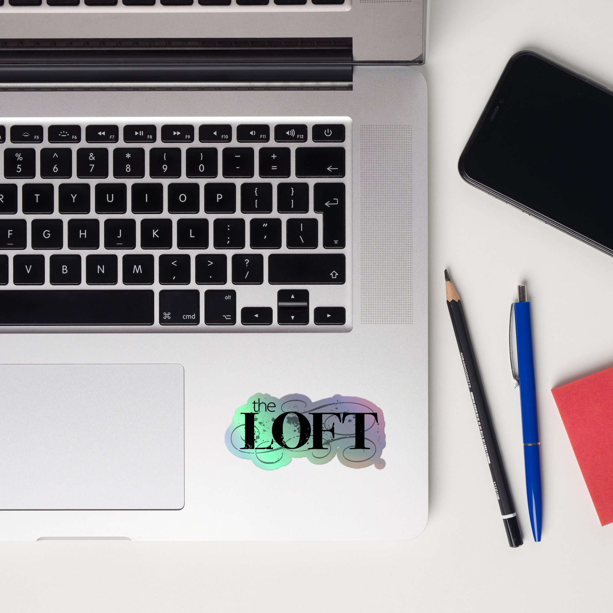 Laptop keyboard displaying the colorful 'the LOFT' holographic sticker.