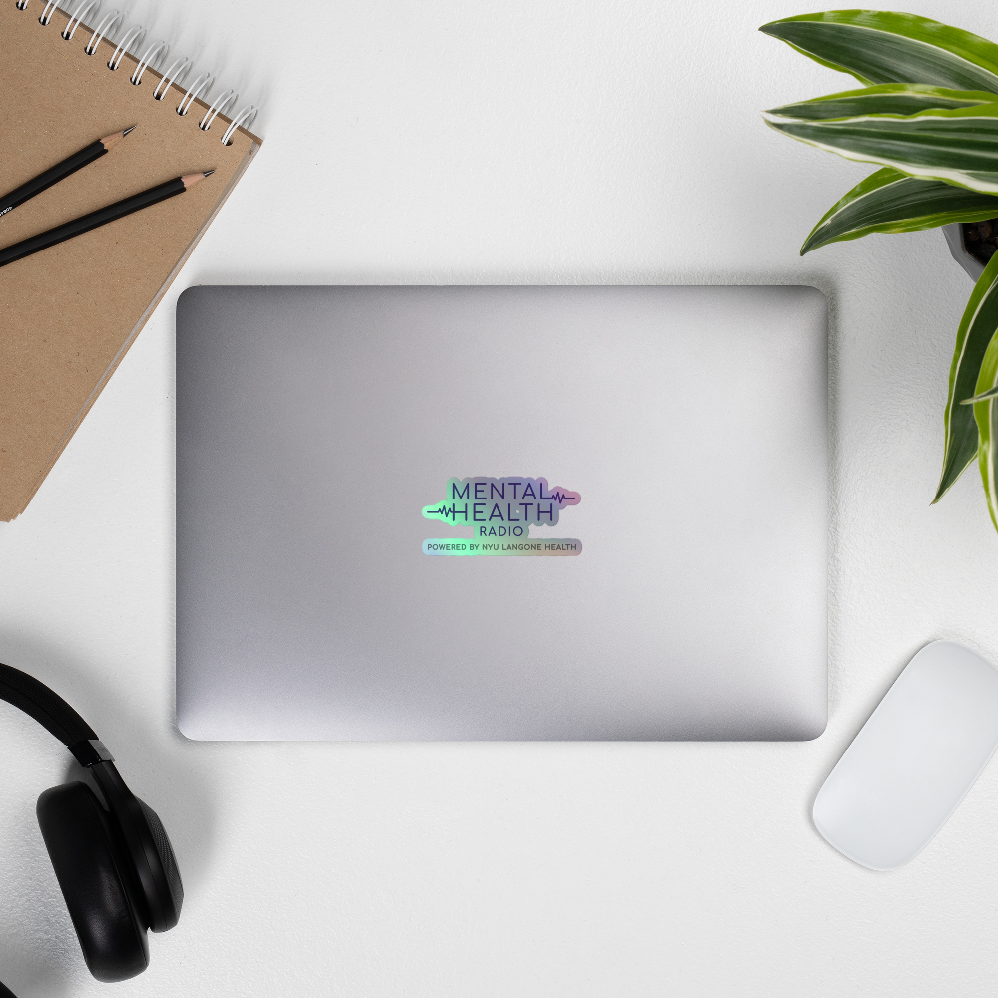 A silver laptop displaying a 'Mental Health Radio' holographic sticker.