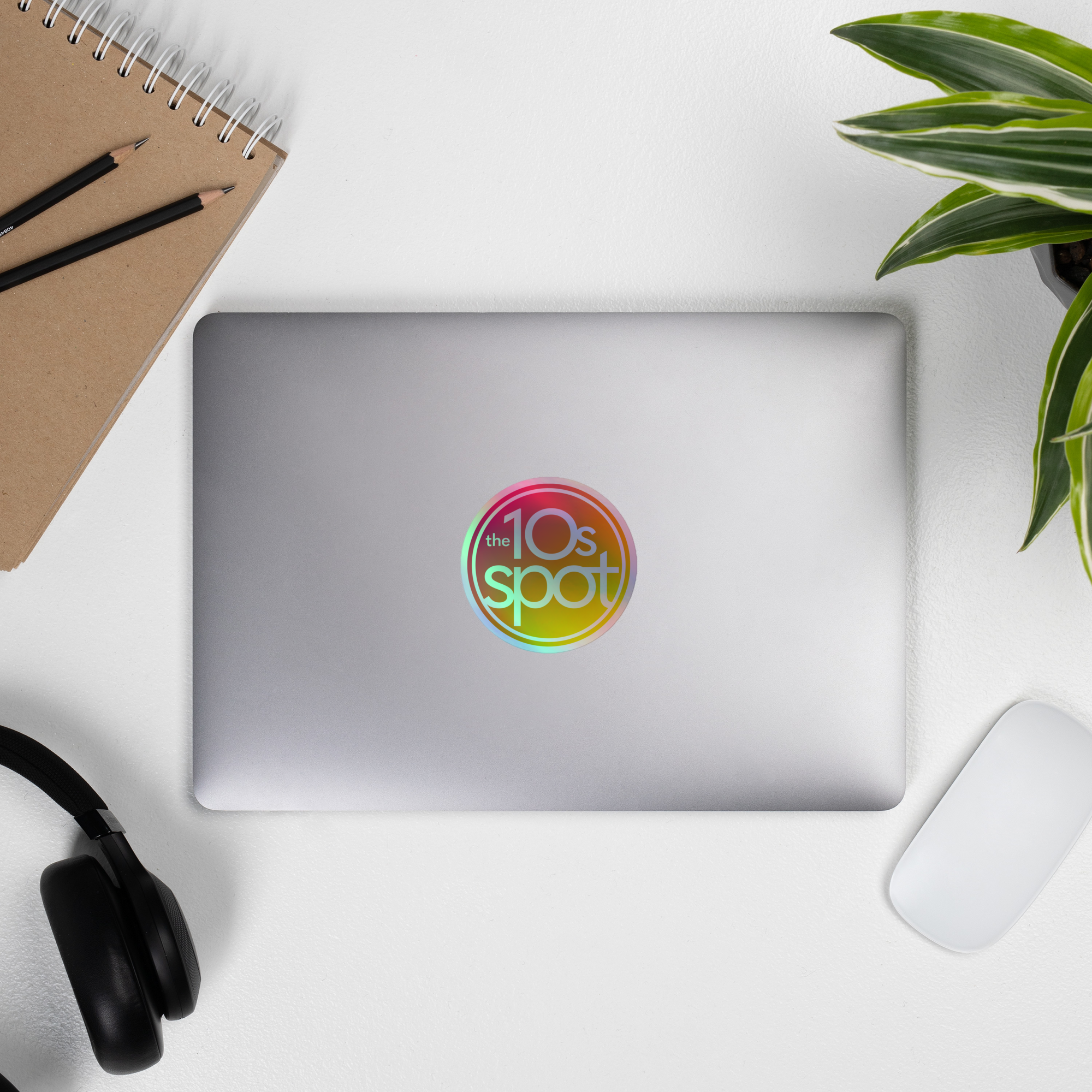 Laptop displaying a colorful 'the 10s spot' holographic sticker.