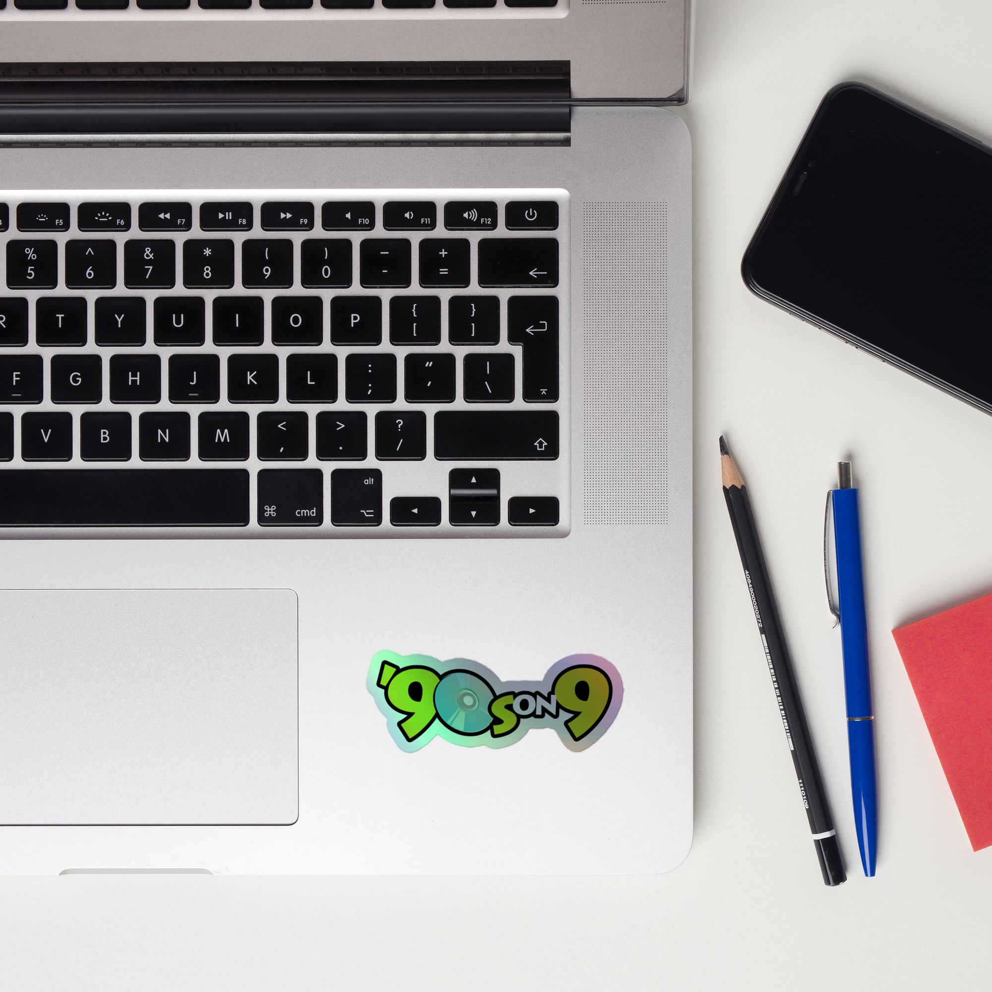 Laptop keyboard displaying a colorful '90s on 9' holographic sticker.