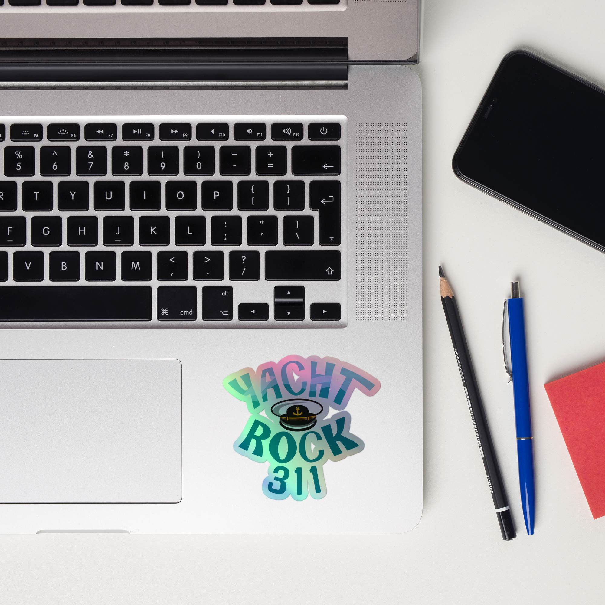 Laptop keyboard displaying a colorful 'Yacht Rock 311' holographic sticker.