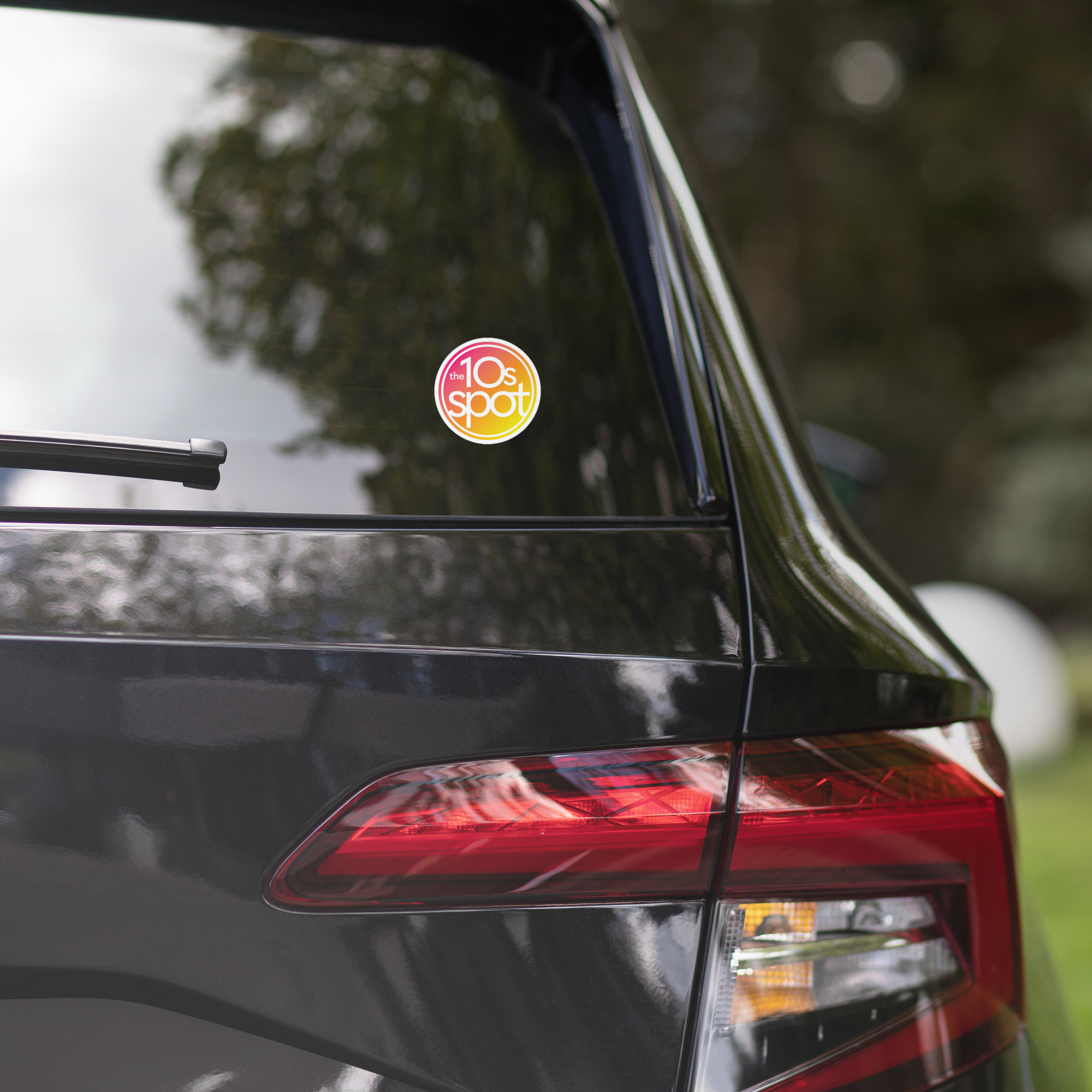 A black car's rear window features a 'The 10s Spot' sticker.