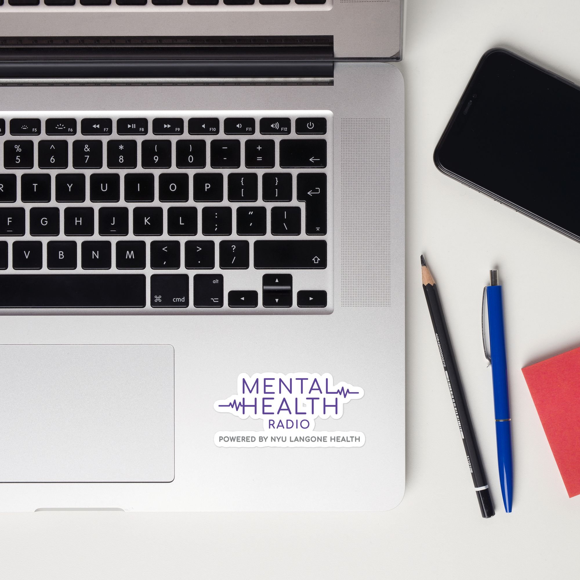 Laptop keyboard displaying a 'Mental Health Radio powered by NYU Langone Health' sticker.