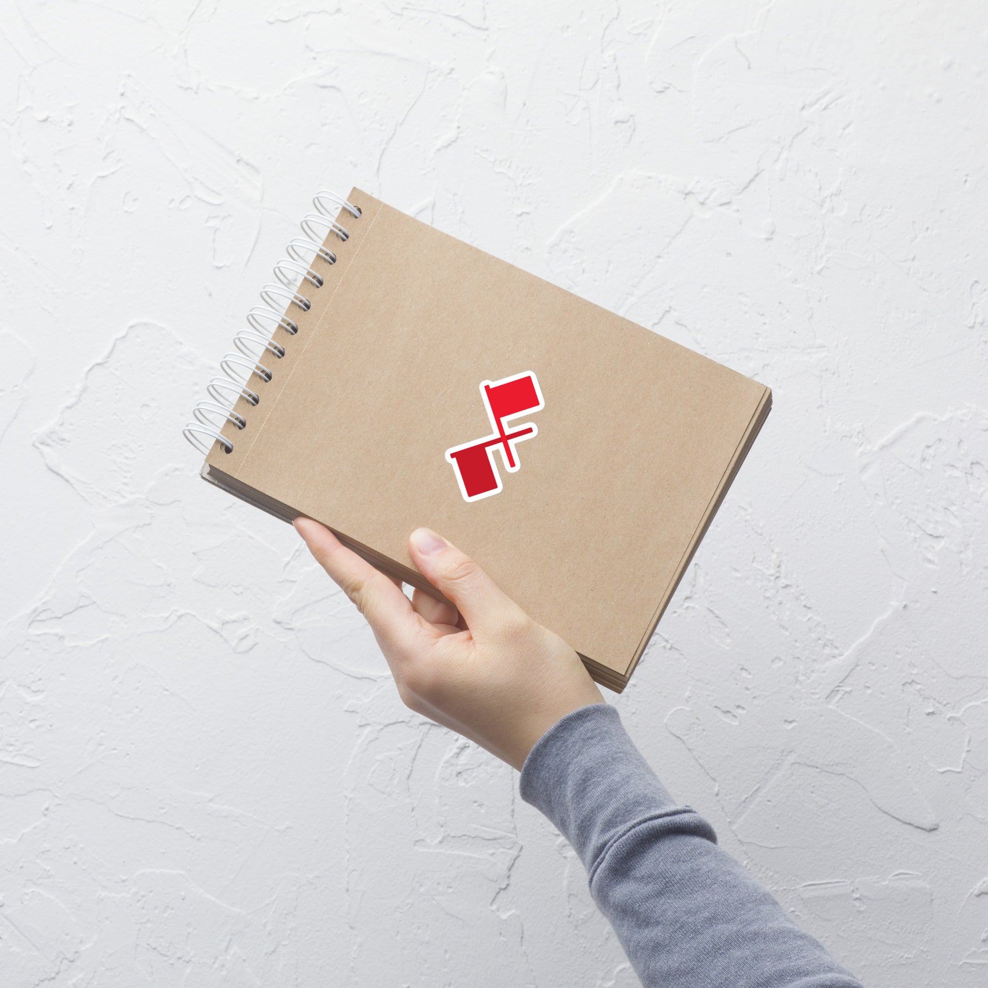 A spiral-bound notebook with a red crossed flags sticker on the cover.