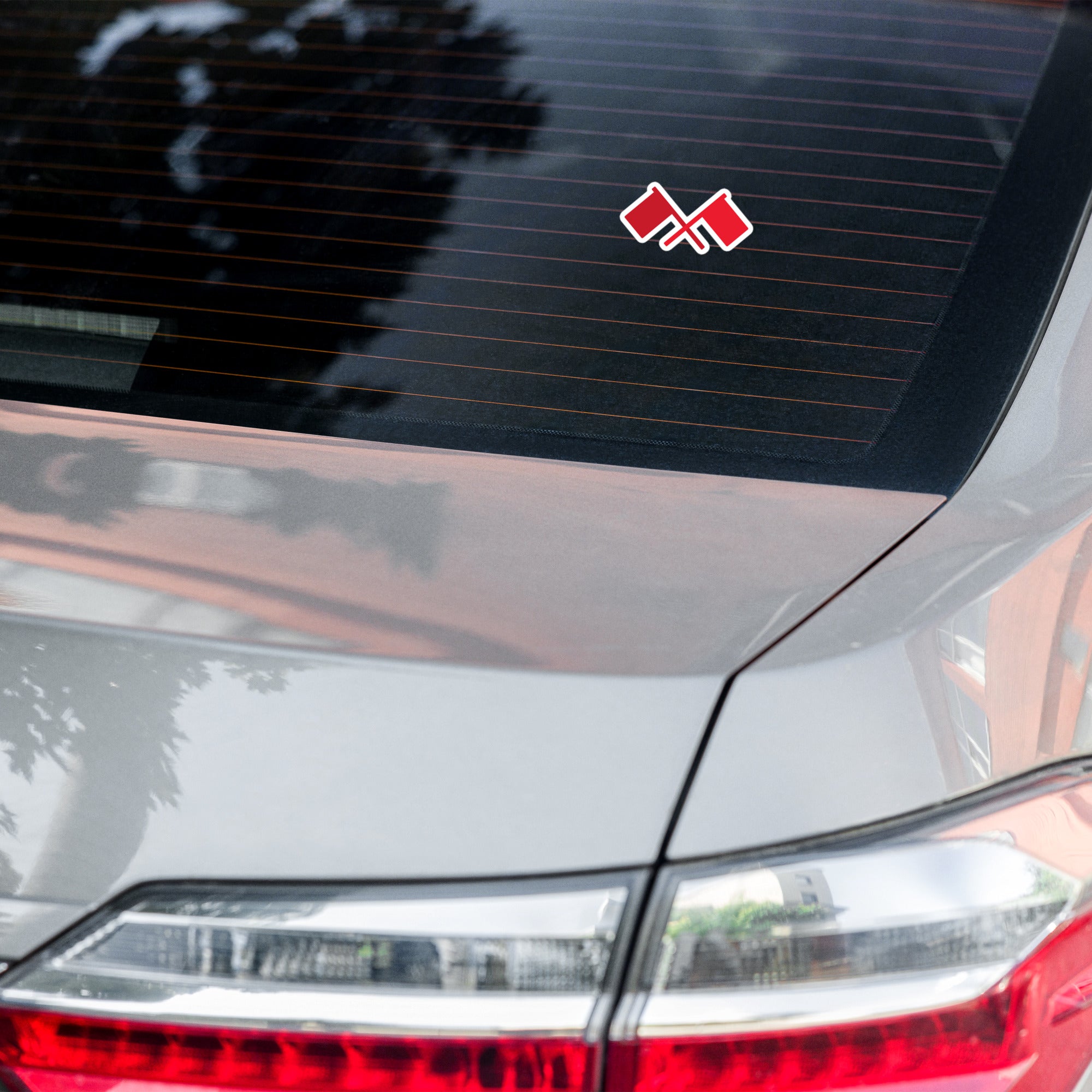 Car with a crossed red flags sticker on rear window.