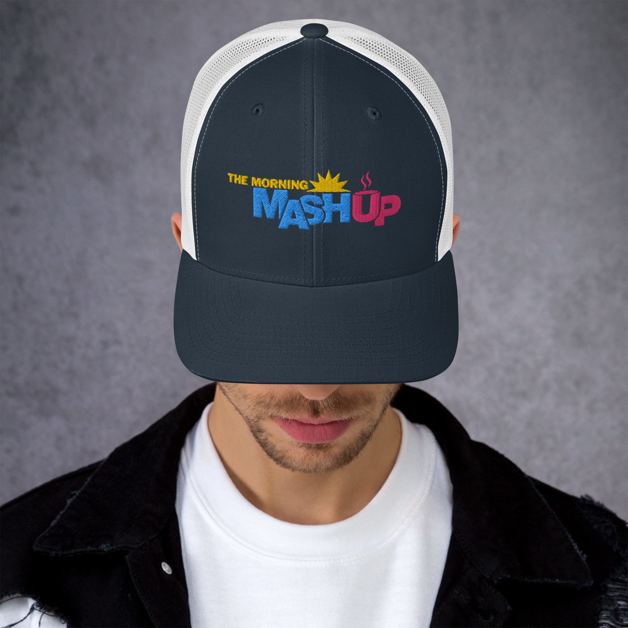 A black and white trucker hat featuring the logo 'THE MORNING MASH Up' with colorful blue, pink and yellow text including a sun and a coffee cup.