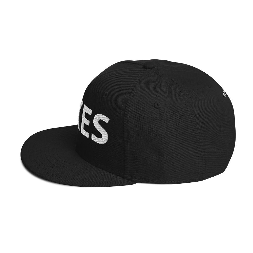 Side view of black hat with light grey letters on front.