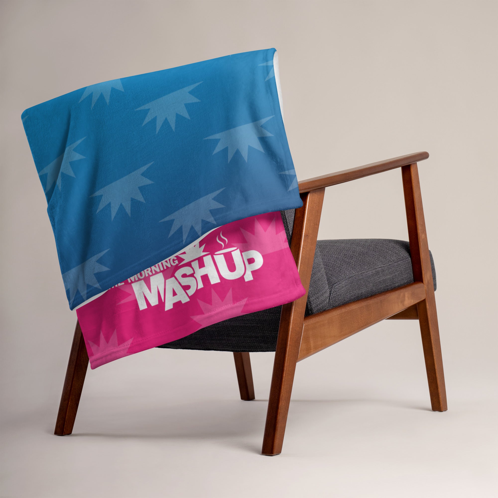 A blue and pink blanket with a starburst pattern draped over the back of a wooden chair. The pink section features the text 'MORNING MASHUP' in bold white letters.