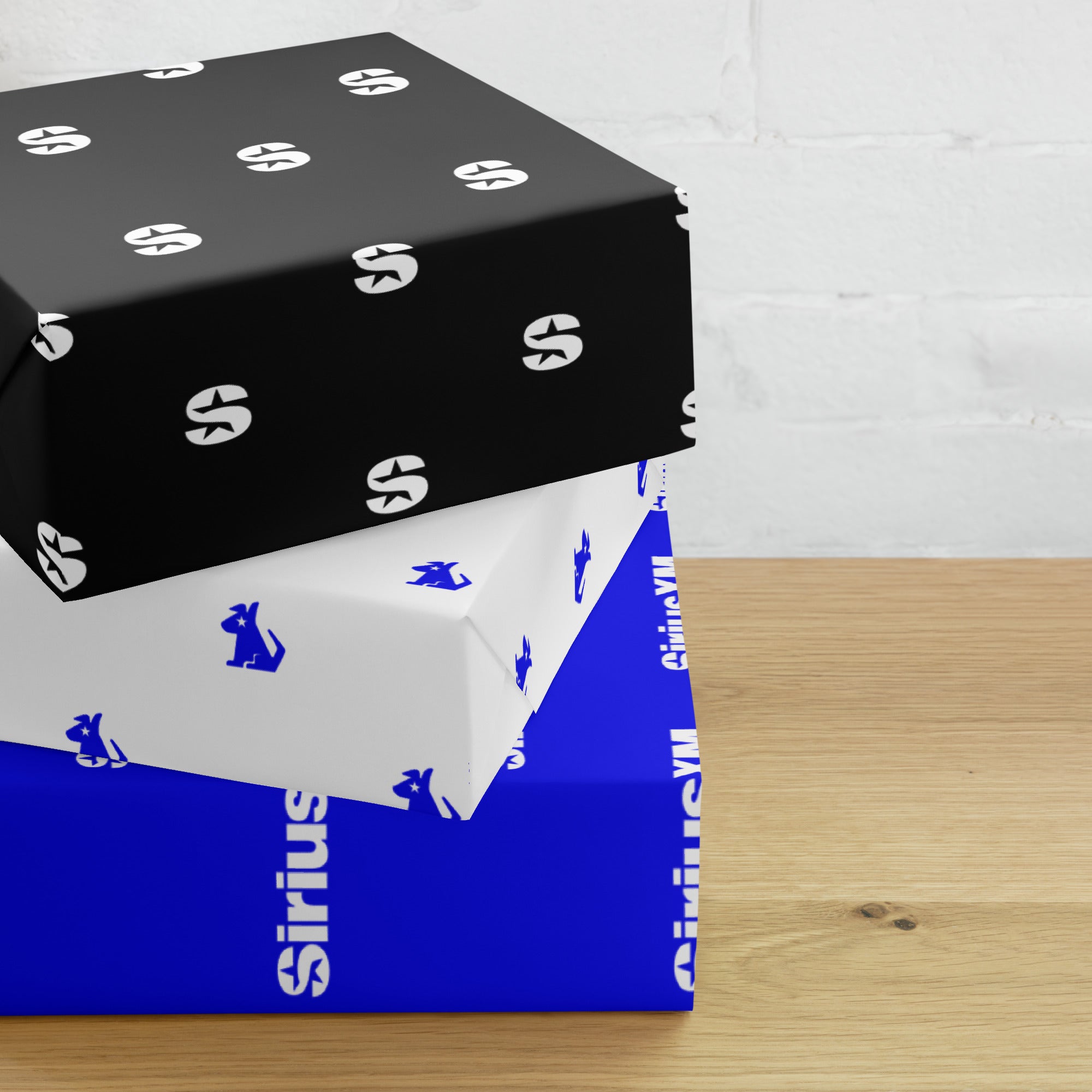 Three stacked gift boxes displaying wrapping paper of in black, white, and blue with 'SiriusXM' branding.