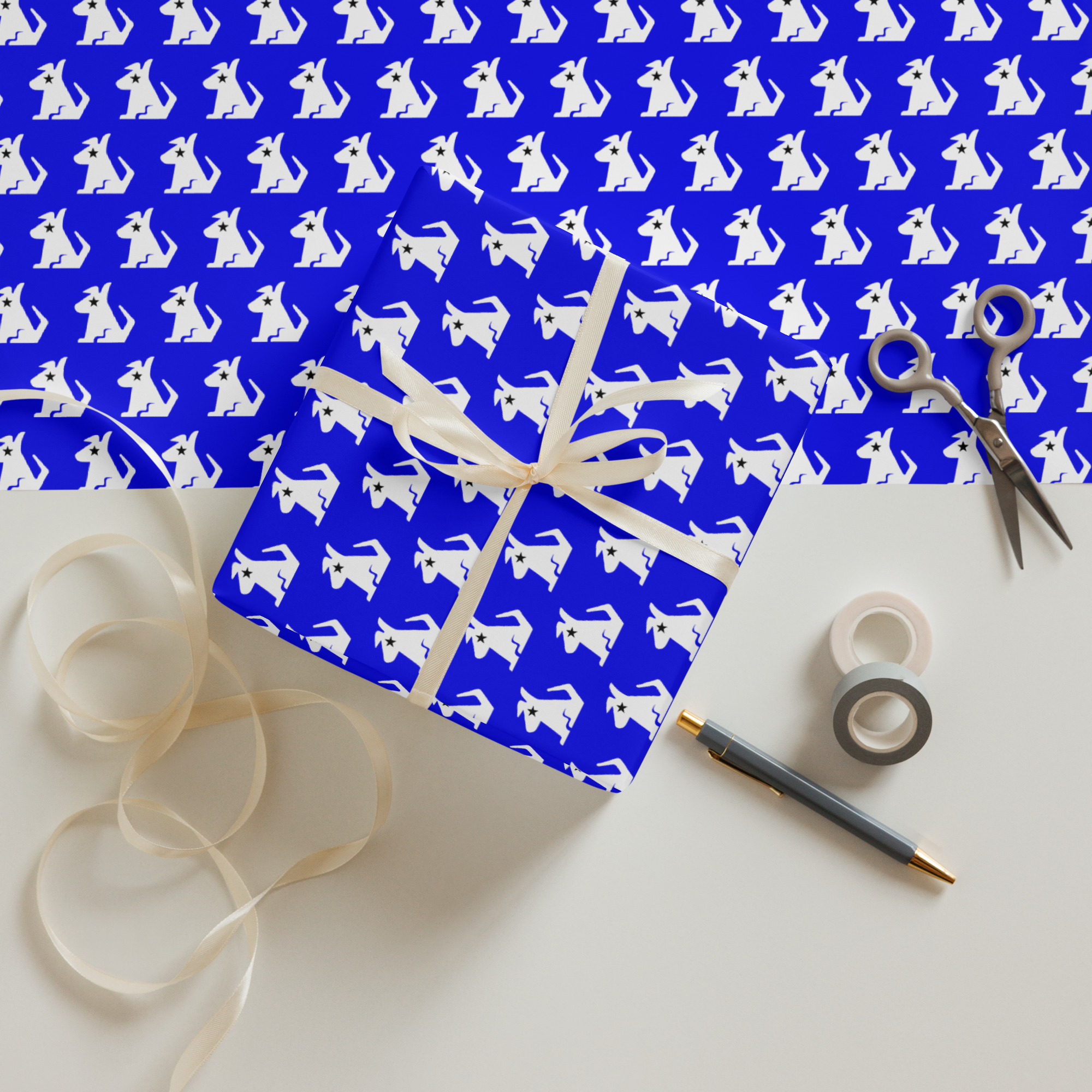 Gift wrapped in blue paper with white dog pattern, adorned with a ribbon, surrounded by scissors and tape on a flat surface.