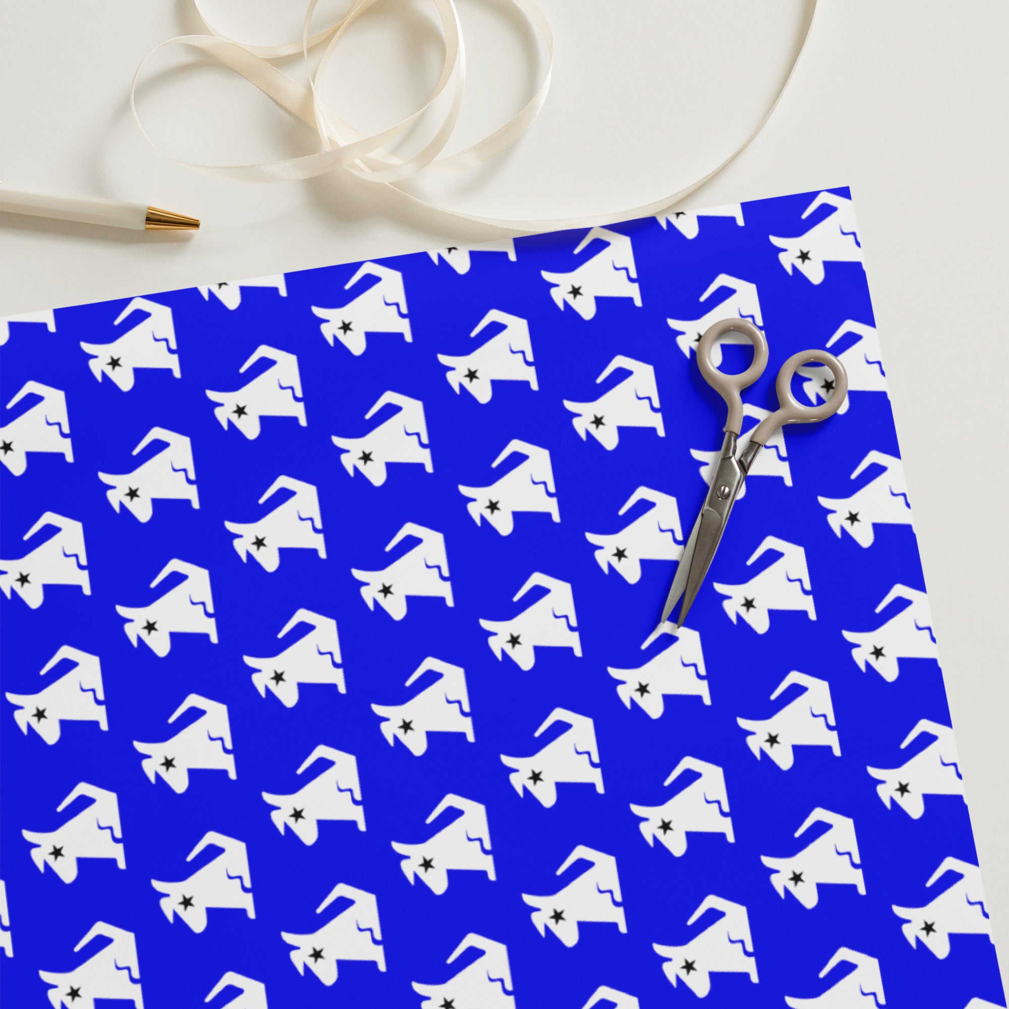 Patterned blue wrapping paper with white dog designs and scissors on a table.